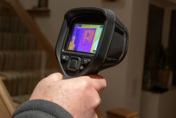 Plumber using advanced equipment to detect a hidden water leak in a home.